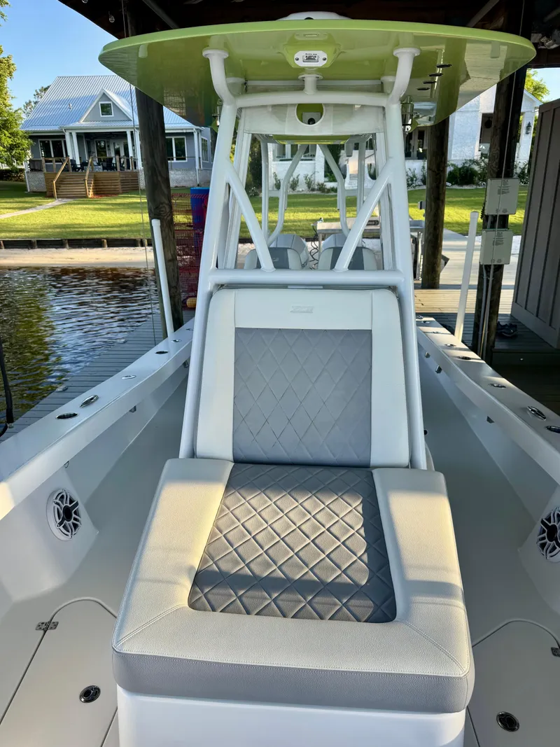 Slide: The Image of 2023 ZCB Freemason 26 boat with cushioned seating, docked near waterfront homes. - 7