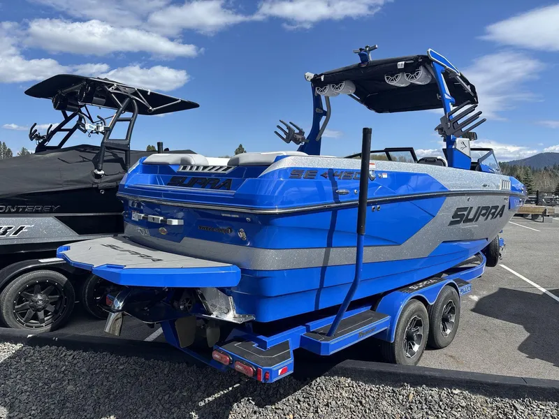 Slide: The Image of 2022 Supra SE 450 boat in vibrant blue, parked on a trailer under a clear sky. - 3