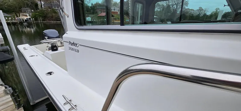 Slide: The Image of 2014 Parker 2520 XLD Sport Cabin boat docked by a serene waterfront. - 17