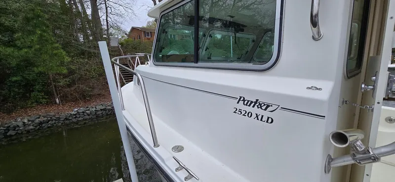 Slide: The Image of 2014 Parker 2520 XLD Sport Cabin boat docked near wooded shoreline. - 18