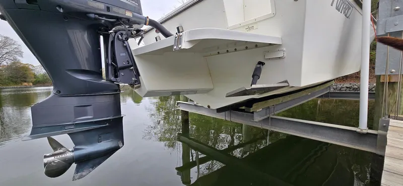 Slide: The Image of 2014 Parker 2520 XLD Sport Cabin boat on lift, showing outboard motor and hull. - 21