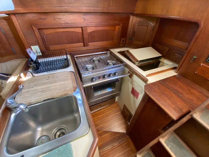 Slide: The Image of 1986 Pacific Seacraft Crealock 37 galley with stove, sink, and wooden cabinetry. - 14