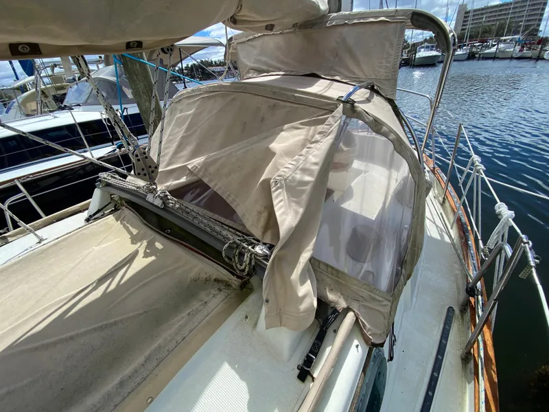 Slide: The Image of 1986 Pacific Seacraft Crealock 37 sailboat with beige canvas cover at marina. - 30