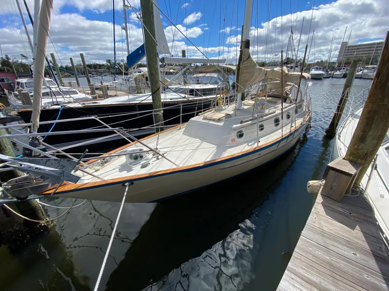 Slide: The Image of 1986 Pacific Seacraft Crealock 37 sailboat docked in a marina under a partly cloudy sky. - 4