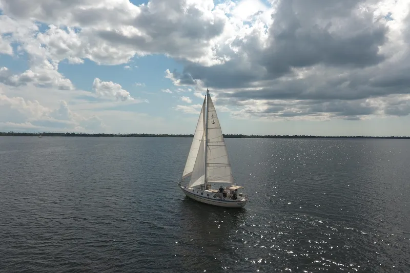 Slide: The Image of Sailboat Pacific Seacraft Crealock 37, 1986, gliding on calm waters under cloudy sky. - 42