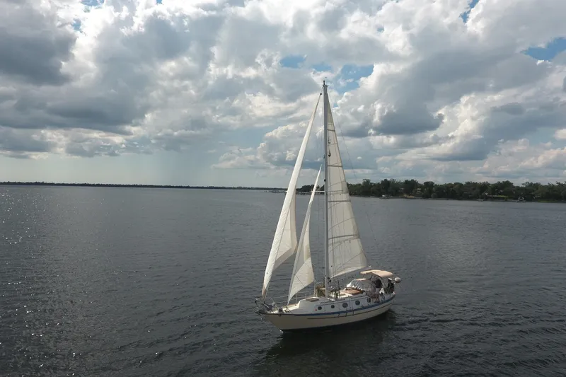 Slide: The Image of Sailboat Pacific Seacraft Crealock 37 (1986) cruising on a calm lake under cloudy skies. - 44