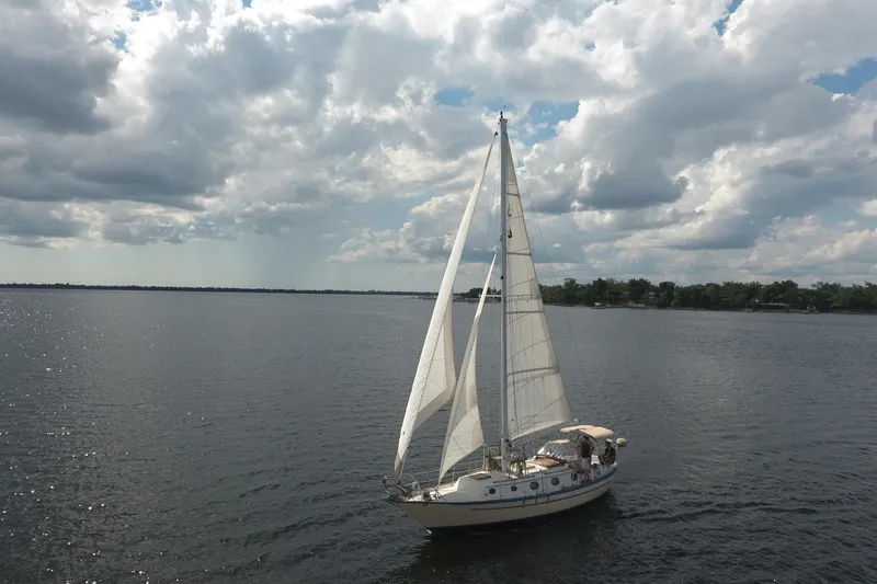 Slide: The Image of 1986 Pacific Seacraft Crealock 37 sailboat cruising under cloudy skies on a calm lake. - 45