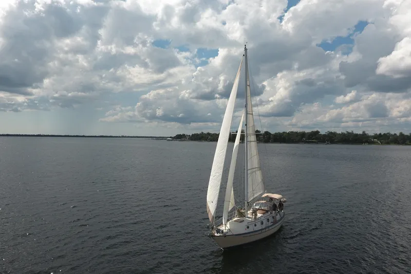 Slide: The Image of 1986 Pacific Seacraft Crealock 37 sailboat cruising under cloudy skies on a calm lake. - 48