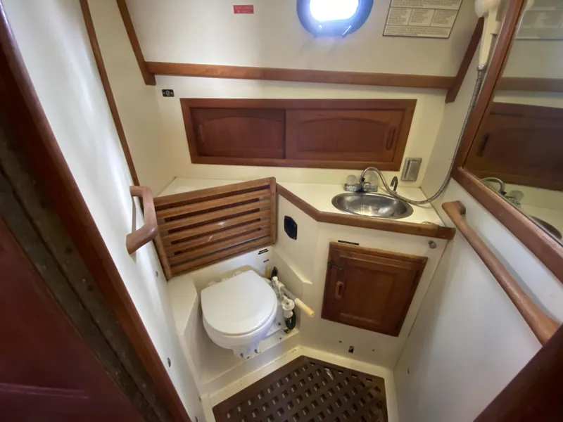 Slide: The Image of 1986 Pacific Seacraft Crealock 37 yacht bathroom with sink, toilet, and wooden cabinetry. - 7