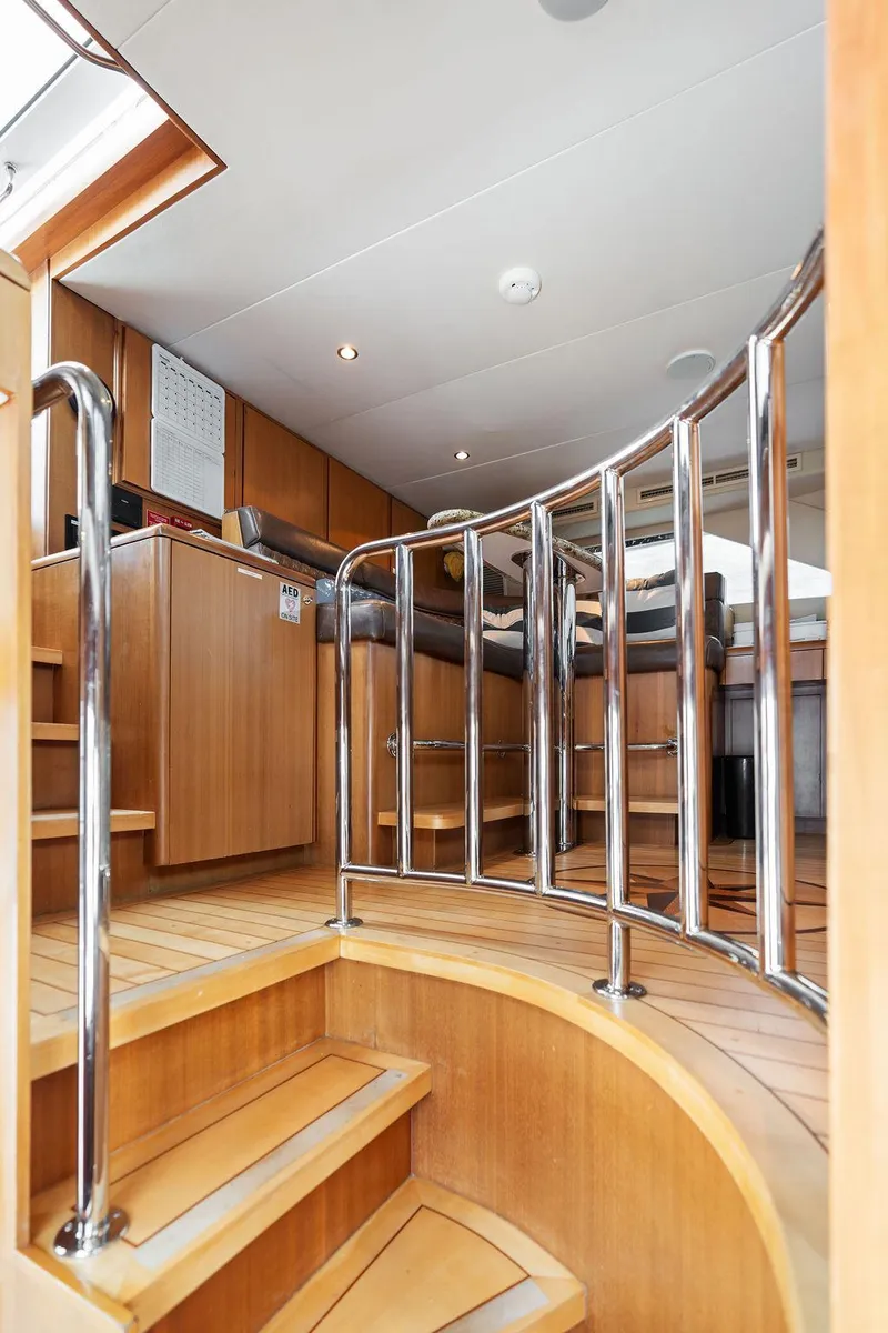 Slide: The Image of Interior staircase of 2004 Hatteras 100 Motor Yacht with wooden finish and metal railings. - 17