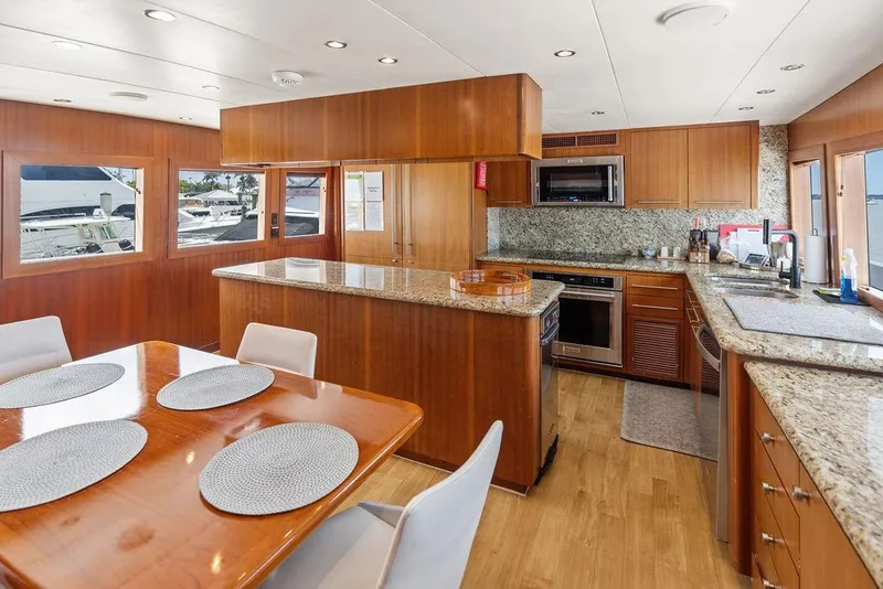 Slide: The Image of Luxurious kitchen and dining area in 2004 Hatteras 100 Motor Yacht, featuring wood cabinetry and granite countertops. - 23