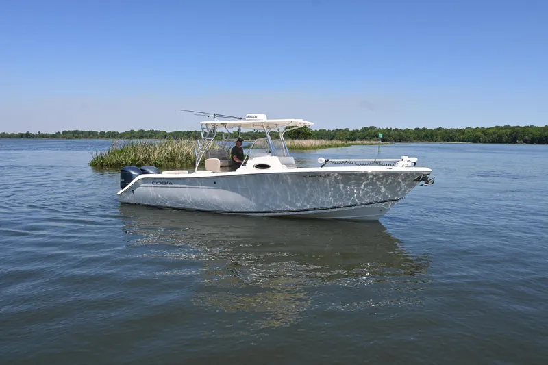 Slide: The Image of 2013 Cobia 296 Center Console boat on calm water under clear blue sky. - 2