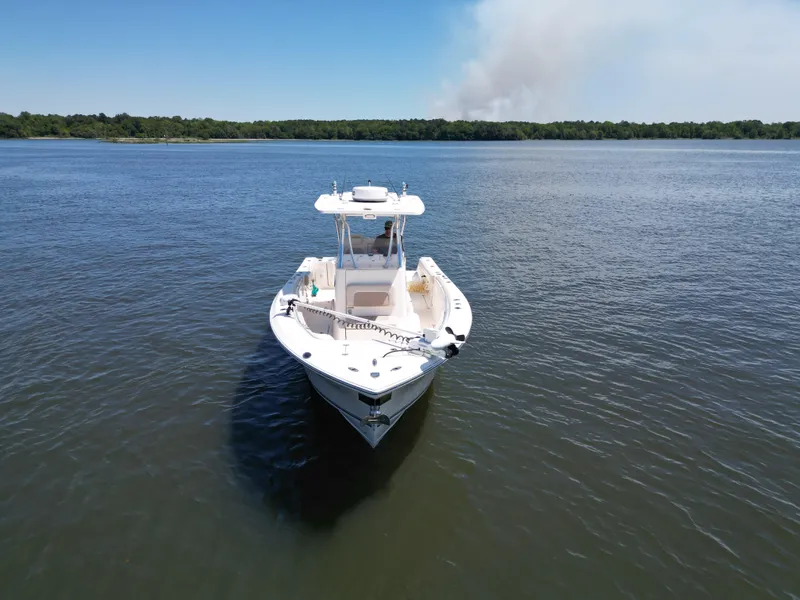 Slide: The Image of 2013 Cobia 296 Center Console boat on calm water, clear sky, and lush shoreline. - 4