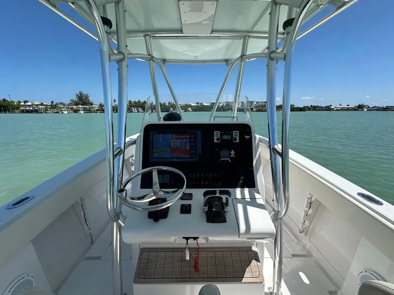 Slide: The Image of 2009 Jupiter 29 FS CC boat helm with steering wheel and navigation system on calm water. - 14