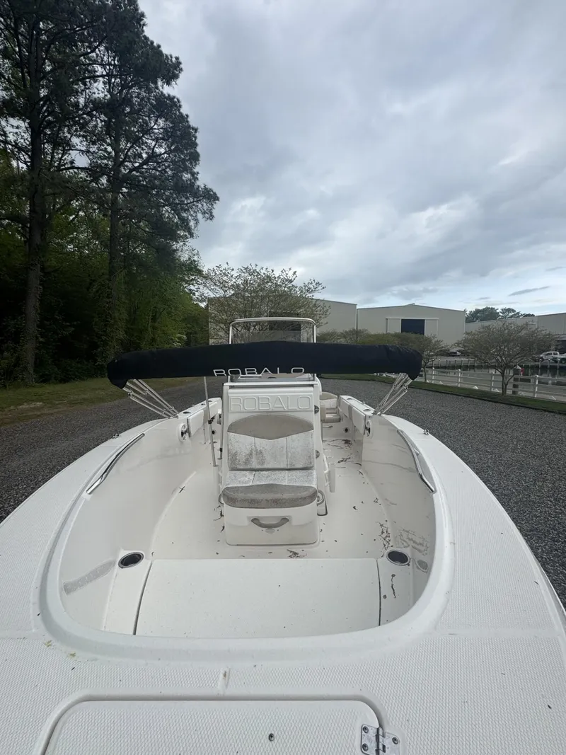 Slide: The Image of 2018 Robalo R180 Center Console boat with canopy, parked outdoors on gravel. - 3
