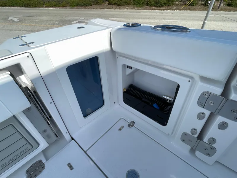 Slide: The Image of 2025 Blackfin 302CC boat interior storage compartment with open hatch and coiled hose. - 13