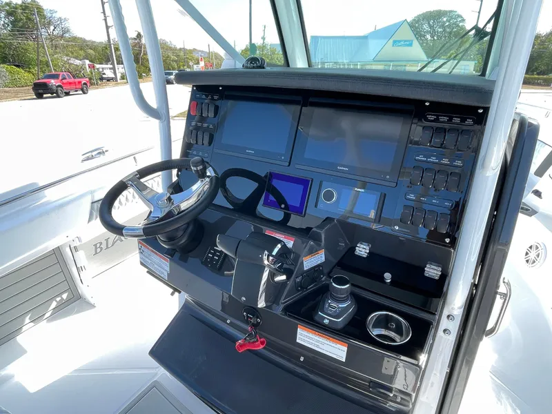 Slide: The Image of 2025 Blackfin 302CC boat dashboard with advanced navigation controls and steering wheel. - 17