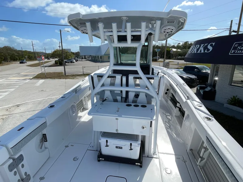 Slide: The Image of 2025 Blackfin 302CC boat with T-top and fishing rod holders, docked under a clear sky. - 9