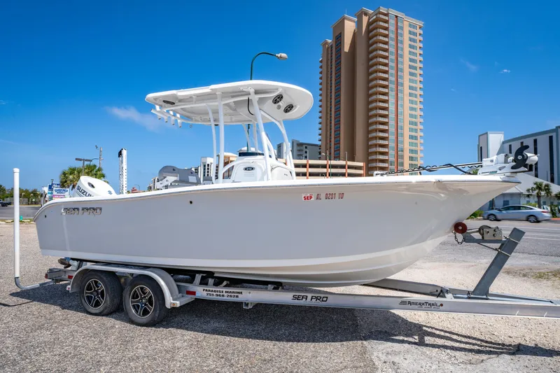 Slide: The Image of 2019 Sea Pro 219 DLX boat on trailer, cityscape background, clear blue sky. - 0