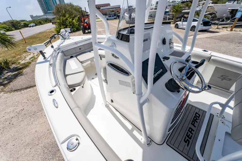 Slide: The Image of 2019 Sea Pro 219 DLX boat interior with steering wheel and seating, parked outdoors. - 18