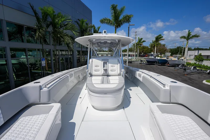 Slide: The Image of 2025 Contender 44ST boat with sleek white seating and modern design, docked near palm trees. - 10