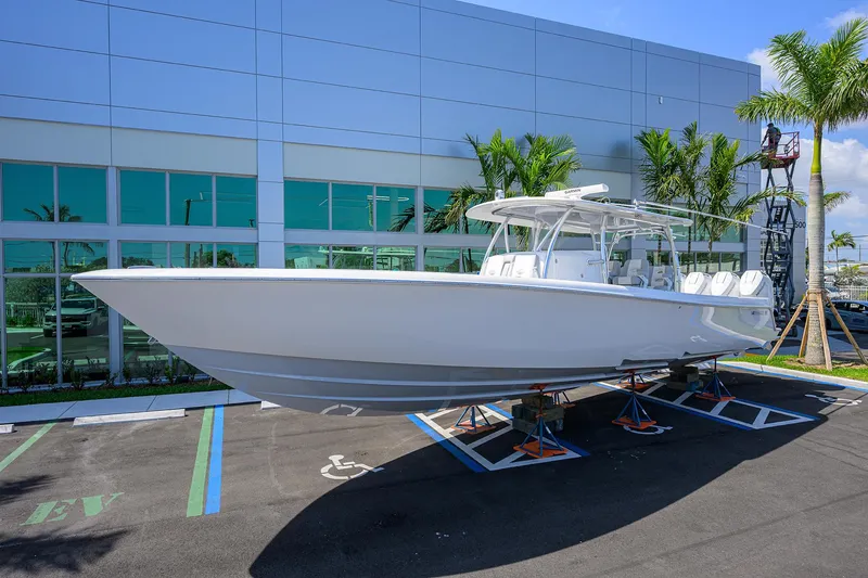 Slide: The Image of 2025 Contender 44ST boat displayed outdoors, elevated on stands, near a modern building. - 2