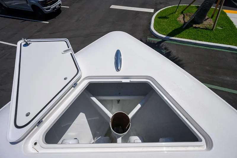 Slide: The Image of 2025 Contender 44ST boat anchor compartment with open hatch, parked on asphalt near green landscaping. - 8