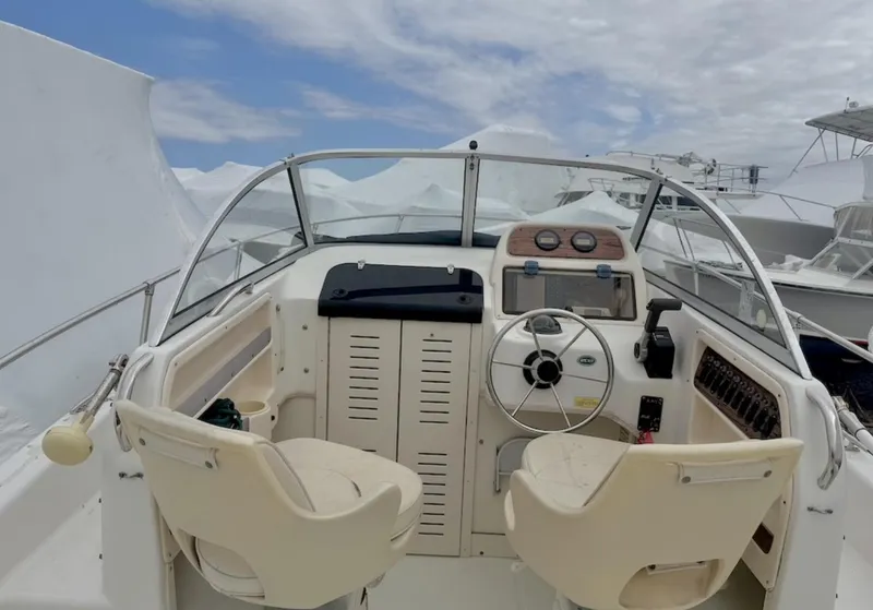 Slide: The Image of 2000 Grady-White Adventure 208 boat cockpit with steering wheel and seats under cloudy sky. - 6