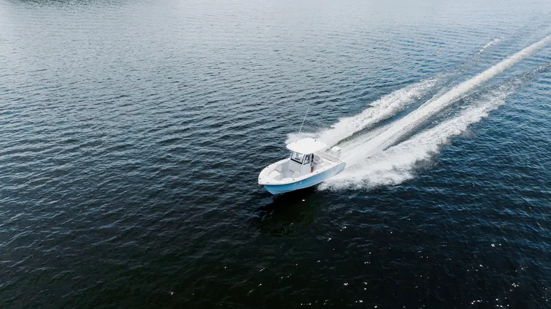 Slide: The Image of 2026 Sea Hunt Ultra 255 SE cruising on a scenic lake with lush green shoreline. - 45