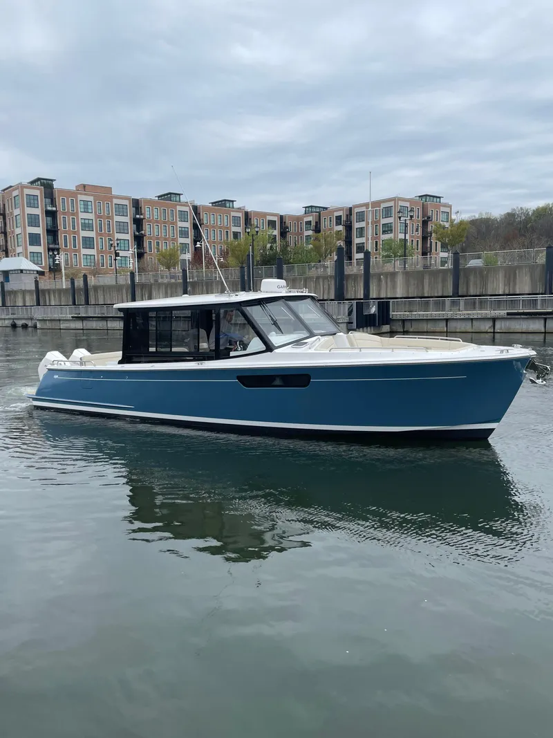 Slide: The Image of 2025 MJM 3 boat in marina, blue hull, modern design, waterfront buildings in background. - 13