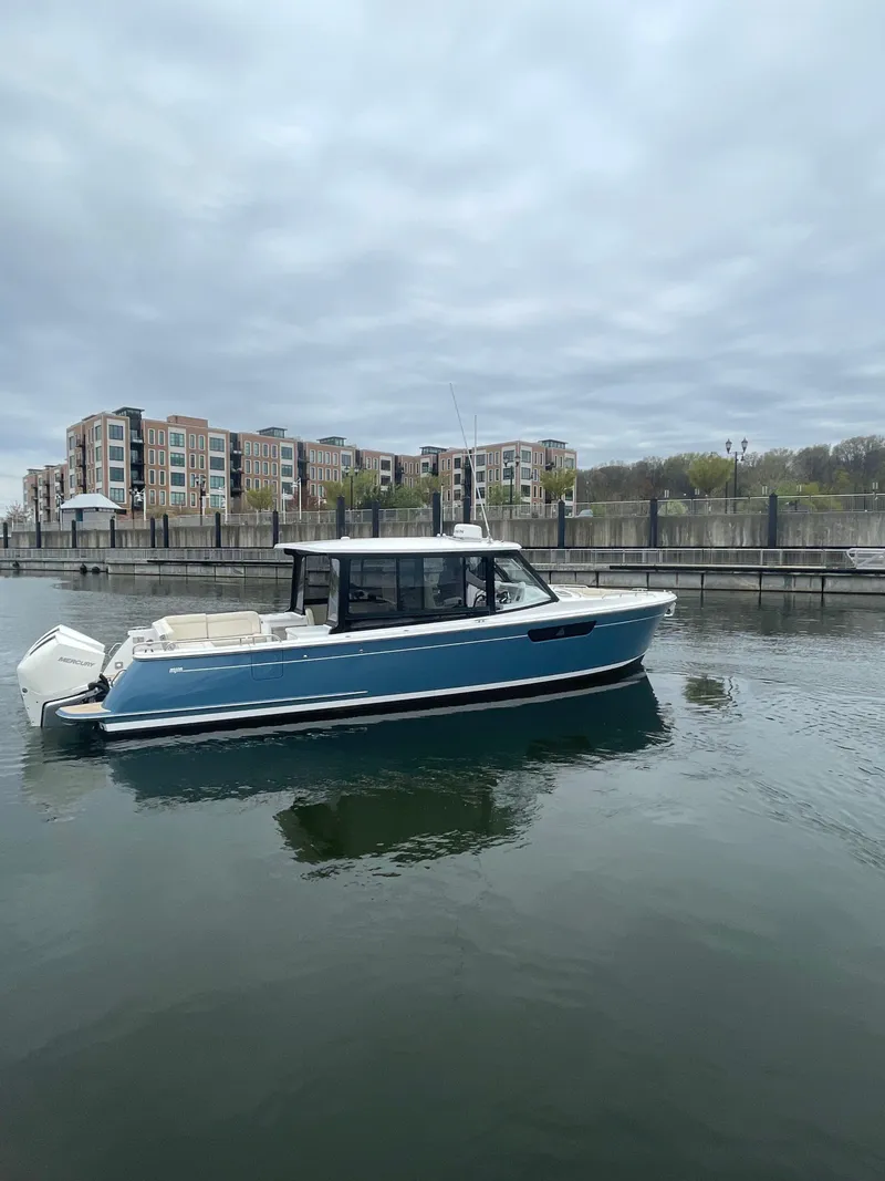 Slide: The Image of 2025 MJM 3 boat docked in a marina with waterfront buildings in the background. - 2