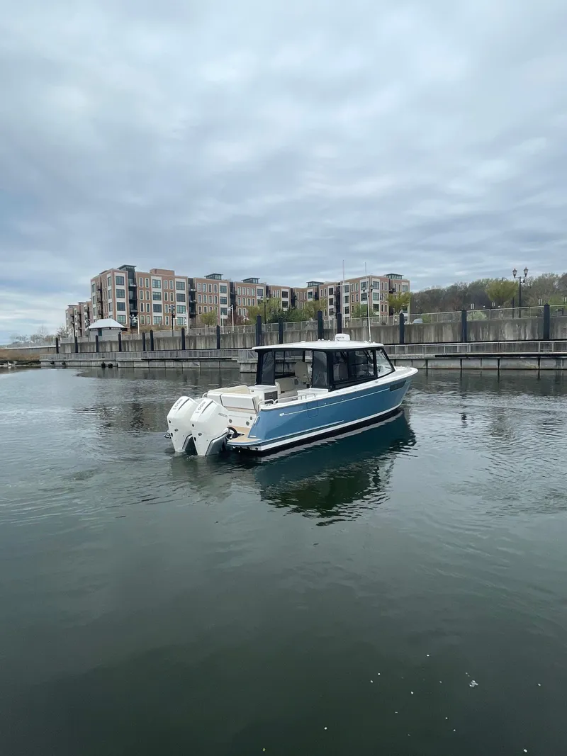 Slide: The Image of 2025 MJM 3 boat on calm water near modern waterfront buildings. - 4