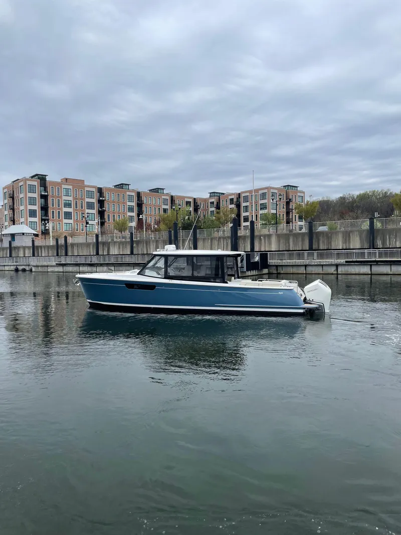 Slide: The Image of 2025 MJM 3 boat docked in a marina with modern buildings in the background. - 7