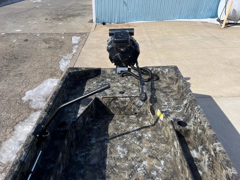 Slide: The Image of Camouflage-patterned Excel Eclipse 2025 boat with motor, parked on concrete surface. - 14