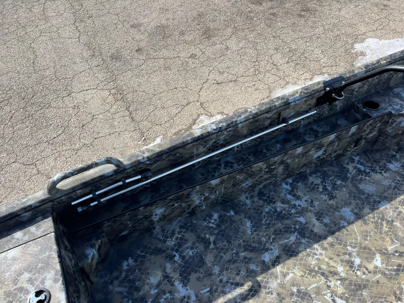 Slide: The Image of 2025 Excel Eclipse boat interior with camouflage design and rod holder on textured flooring. - 15