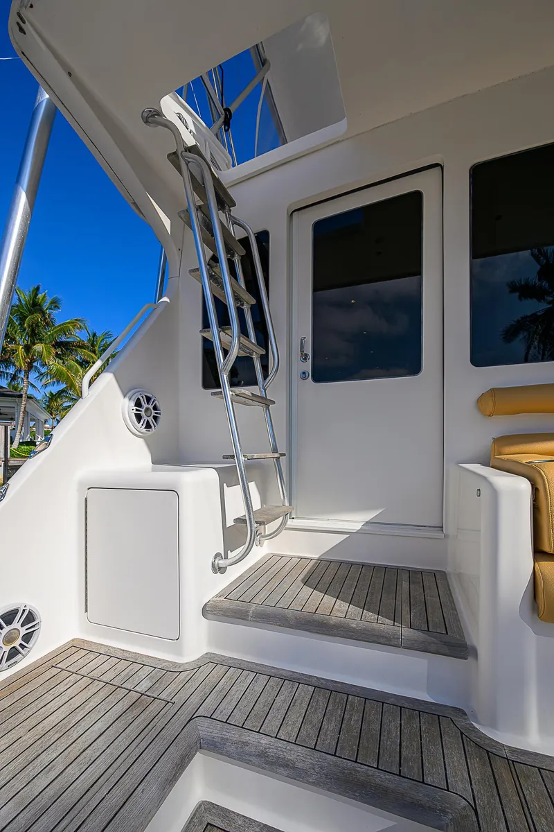 Slide: The Image of 2007 Viking 68 Convertible yacht with teak steps and ladder, under a clear blue sky. - 31
