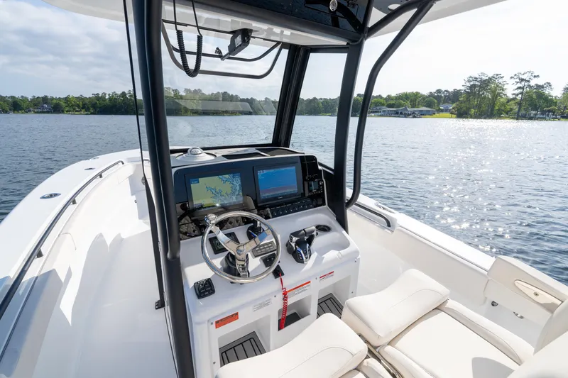 Slide: The Image of 2026 Sea Hunt Gamefish 27 Coffin Box boat interior with navigation screens on a calm lake. - 41