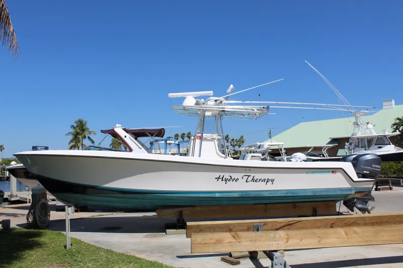 The Image of 2002 Contender 31 CC boat named "Hydro Therapy" on a trailer, clear blue sky background. - 0