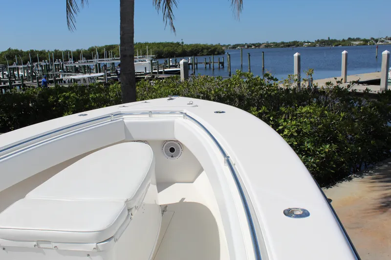 Slide: The Image of 2002 Contender 31 CC boat docked by a scenic waterfront with lush greenery. - 21