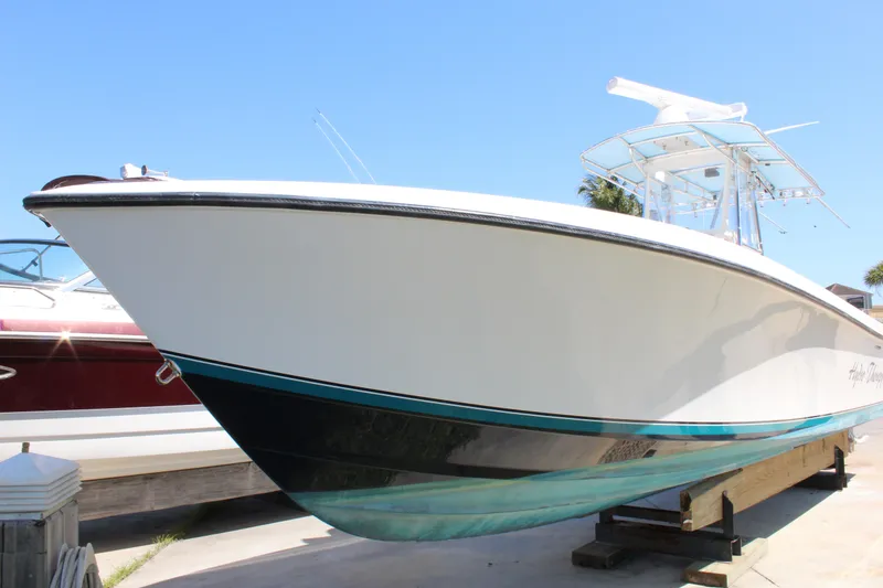 Slide: The Image of 2002 Contender 31 CC boat on display, white hull with teal accents, clear blue sky. - 3