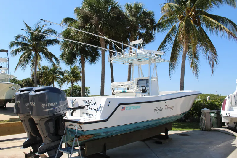 Slide: The Image of 2002 Contender 31 CC boat with dual Yamaha engines, parked near palm trees. - 33