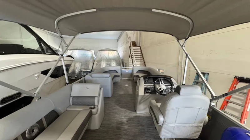 Slide: The Image of 2023 Bennington 25 LSB pontoon boat interior with seating and helm, under canopy. - 10