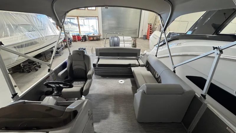 Slide: The Image of 2023 Bennington 25 LSB pontoon boat interior with seating and helm in a showroom. - 17
