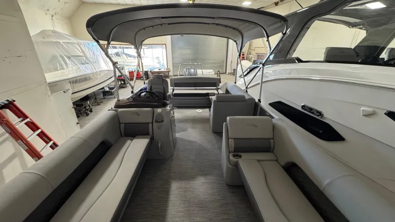 Slide: The Image of 2023 Bennington 25 LSB pontoon boat interior with spacious seating and canopy in a showroom. - 19