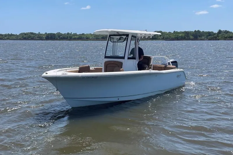 Slide: The Image of 2021 Sea Hunt 239 Ultra SE boat cruising on a calm lake under a clear sky. - 0