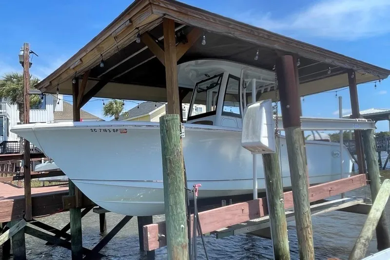 Slide: The Image of 2021 Sea Hunt 239 Ultra SE boat docked under a wooden shelter. - 10