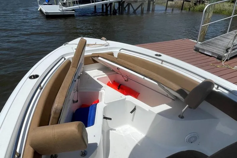 Slide: The Image of 2021 Sea Hunt 239 Ultra SE boat interior with seating and storage, docked by the water. - 12