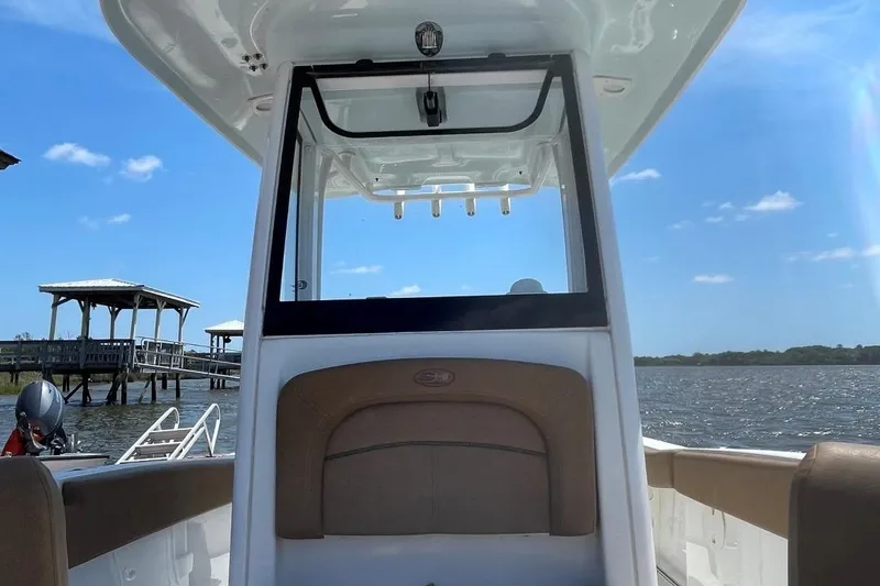 Slide: The Image of 2021 Sea Hunt 239 Ultra SE boat on water, clear sky, dock in background. - 14