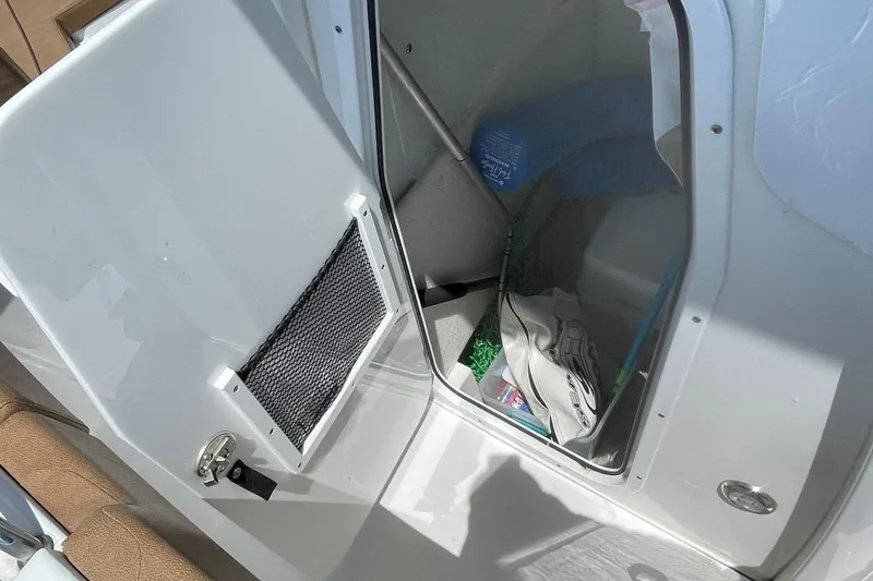 Slide: The Image of 2021 Sea Hunt 239 Ultra SE boat storage compartment with open door and visible interior items. - 16