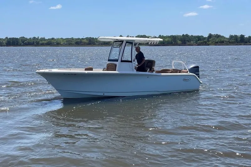 Slide: The Image of 2021 Sea Hunt 239 Ultra SE boat cruising on a calm lake under a clear sky. - 2